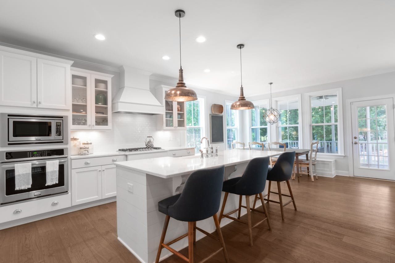 Bright and elegant modern kitchen with white cabinets, dining area, and island bar.